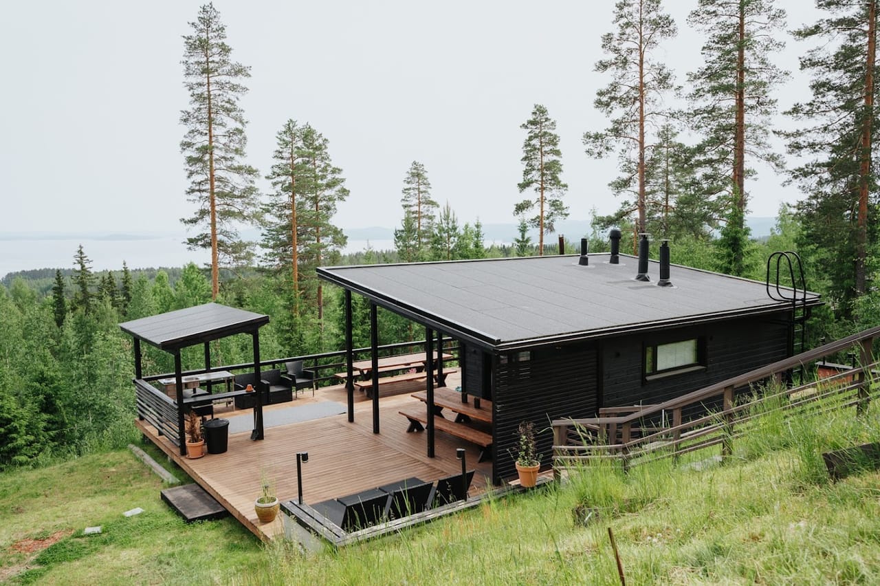Ulkorakennus ja terassi ylhäältä kuvattuna, ympärillä metsä ja järvi