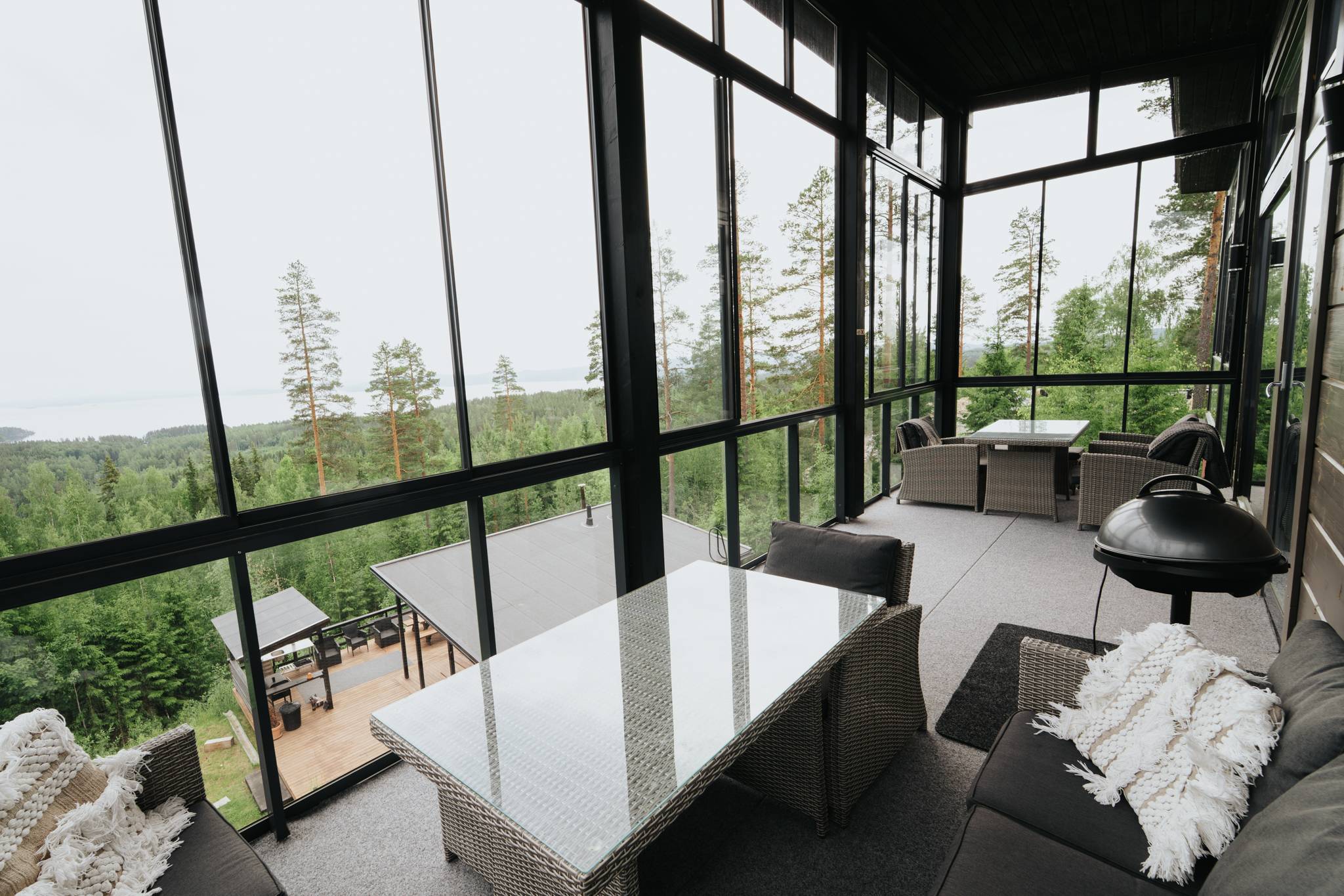 Karhu A spa vuokramökki – lasiseinäinen olohuone ja järvimaisema
