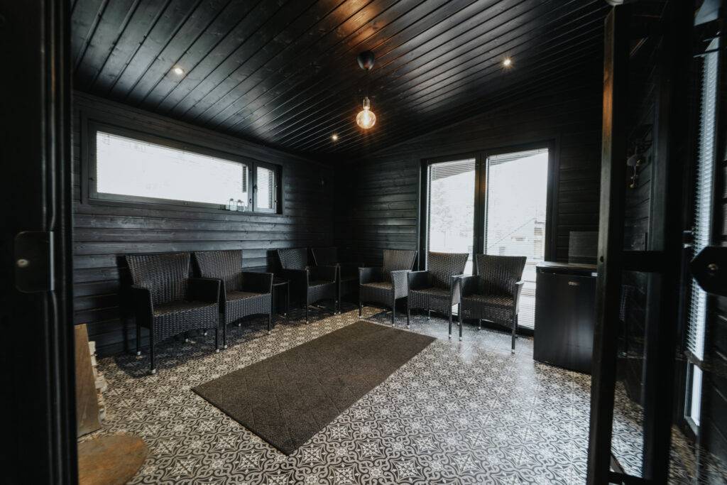 Karhu A spa vuokramökki – lasiseinäinen olohuone ja järvimaisema