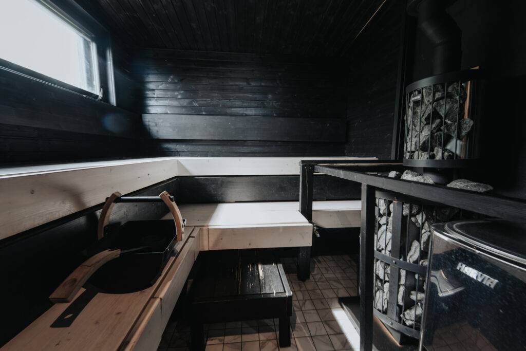 Karhu A spa vuokramökki – lasiseinäinen olohuone ja järvimaisema